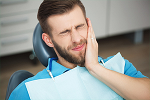 Man in dental chair holding jaw